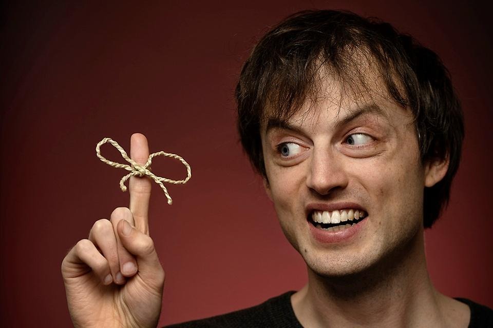 Bild på Jonas von Essen med en rosett knuten på sitt högra pekfinger.