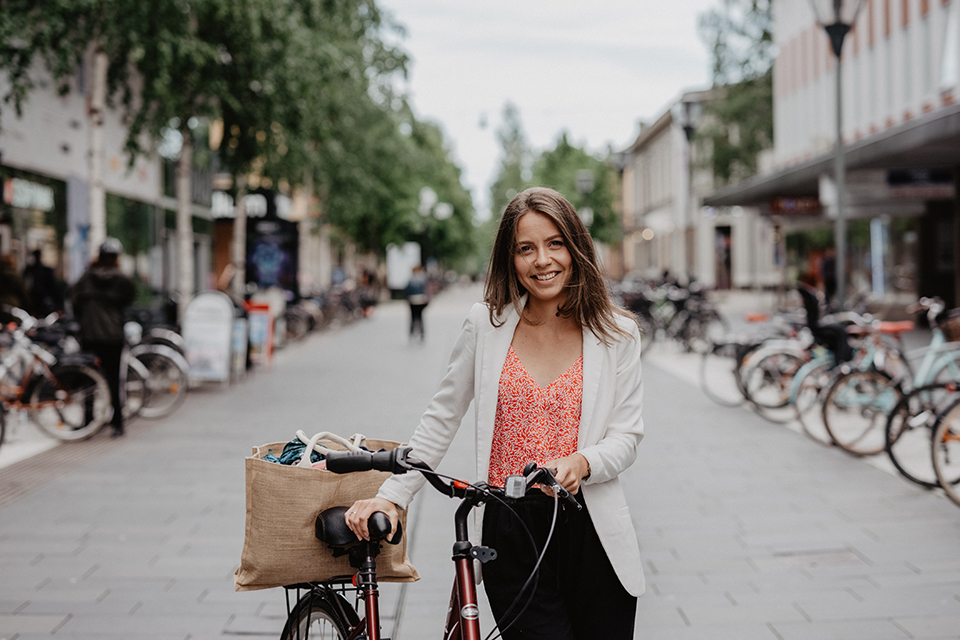 Image of a woman walking and steering a bike in downtown Umeå.