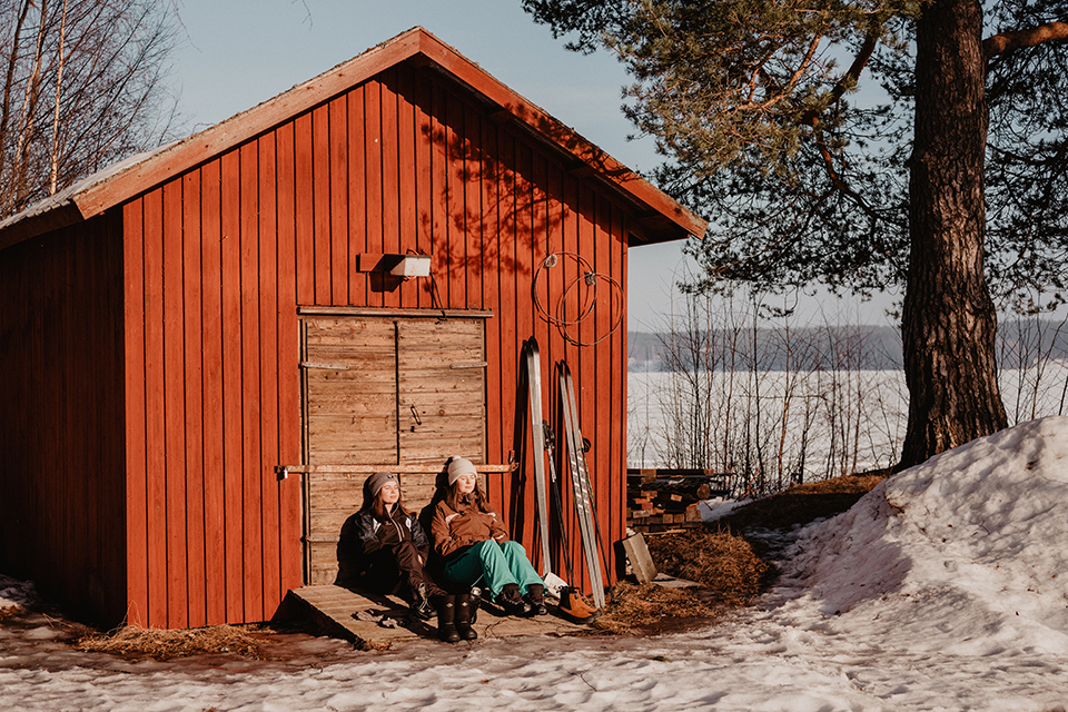Two students hanging out next to a cottage by Tavelsjön.