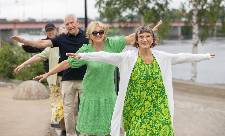 Fem kvinnor och män står på rad och balanserar med utsträckta armar