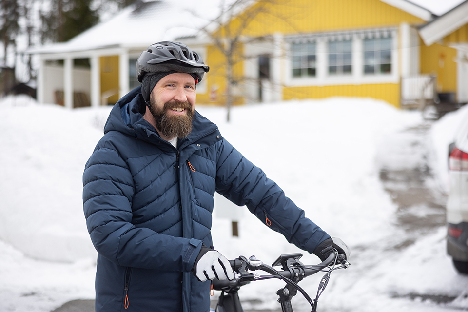 Bilden visar Erik i vinterkläder, bärandes cykelhjälm och poserandes med sin cykel.