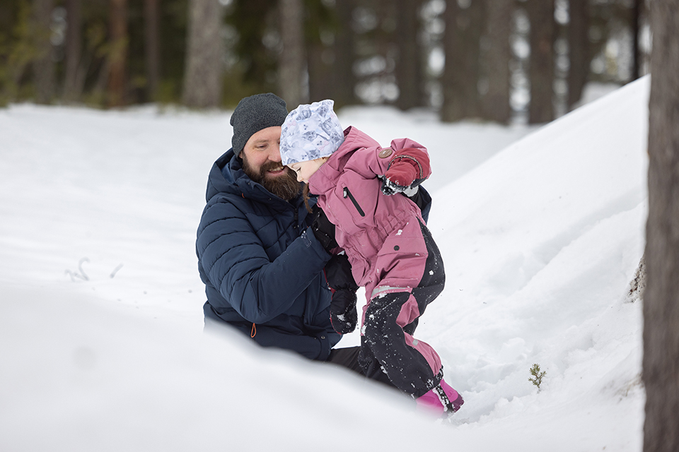 Bilden visar Erik Hortlund som leker i snön med ett av sina barn.