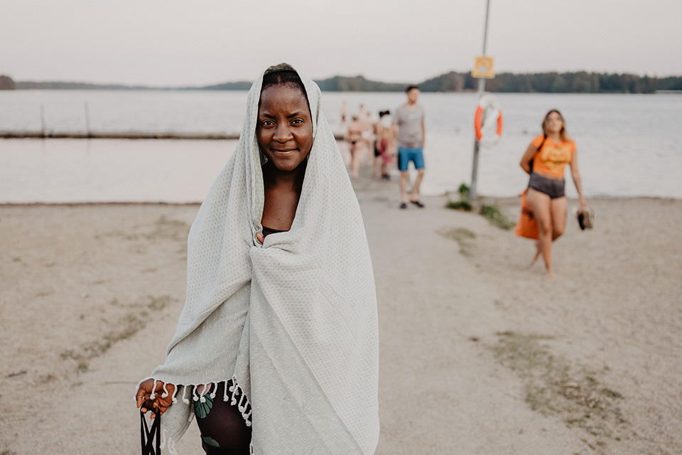A woman wrapped in a towel after taking a swim in a lake.