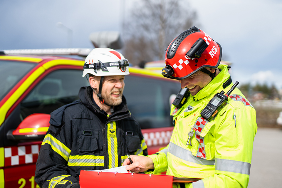 En kvinna och en man i larmställ som går bredvid en brandbil