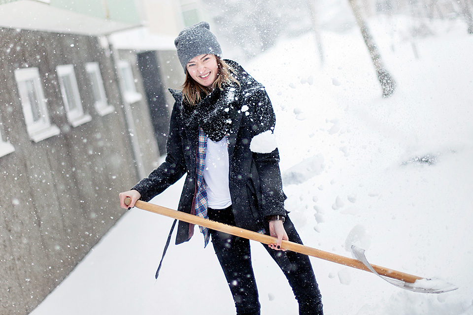 Ung kvinna skottar snö.