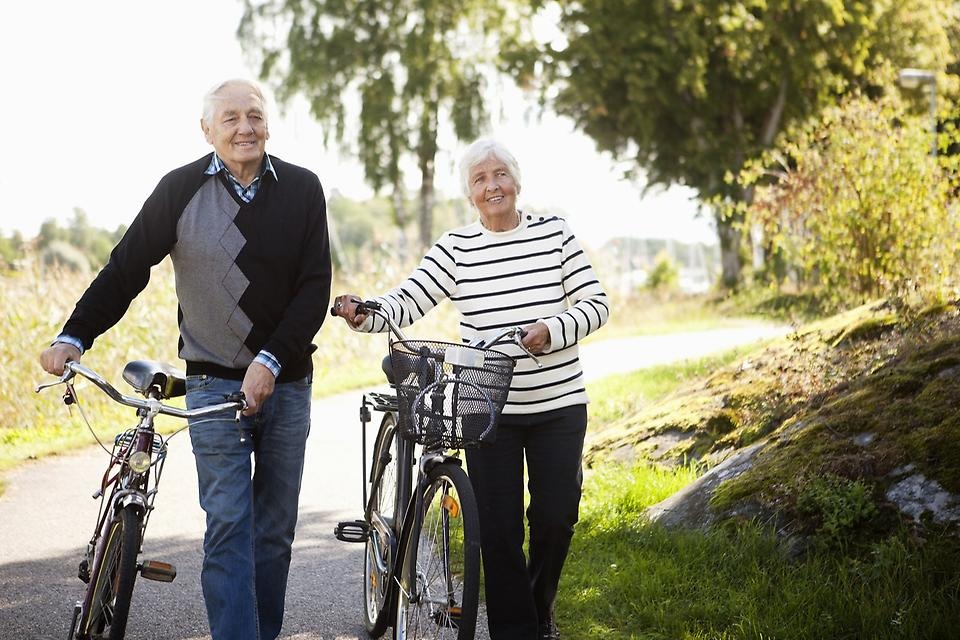 Kvinna och man som styr sina cyklar i somrig miljö