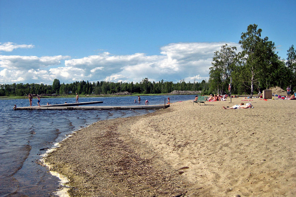 Människor som ligger på stranden, i brygga som går ut i vattnet.