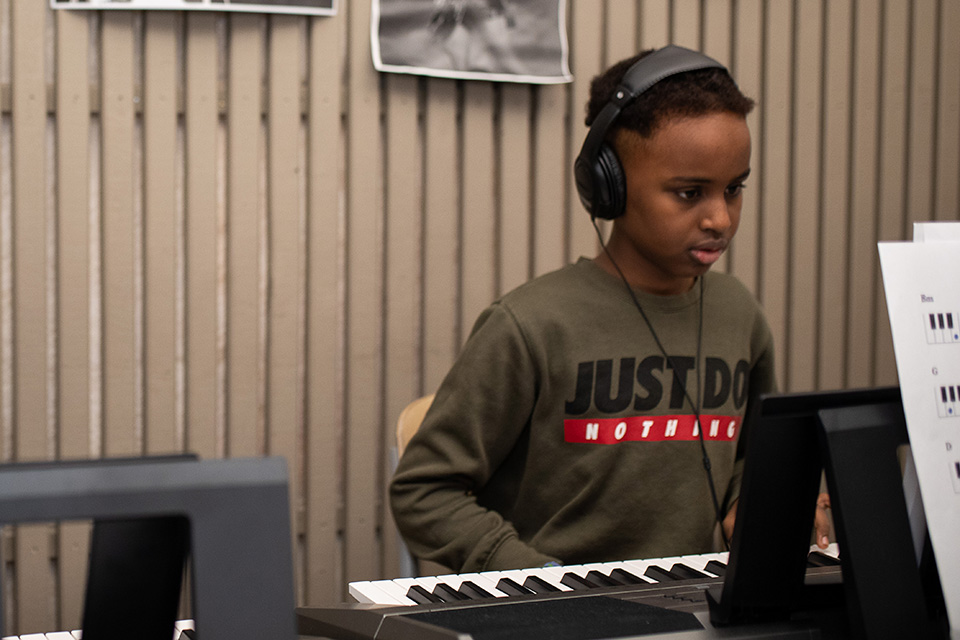Elev spelar synth med hörlurar på.