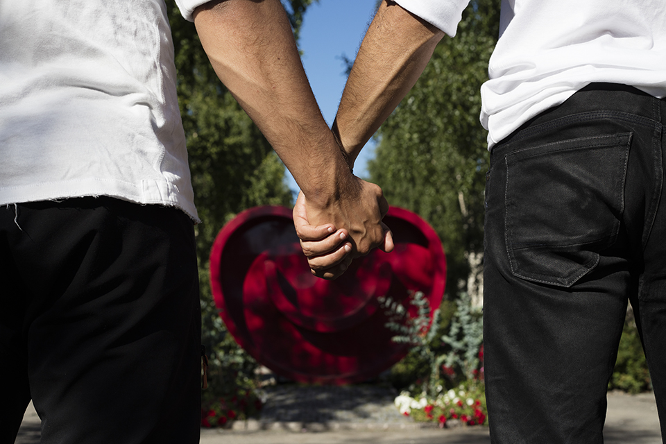 Bilden visar två män som håller hand framför kulturhuvudstadshjärtat.