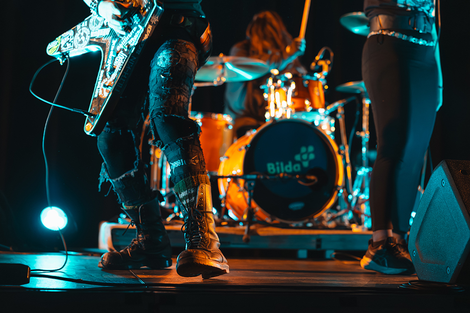 Bild som visar instrument på en scen under rockkonsert. Inte fokus på utövarna som ej syns med ansikte. 