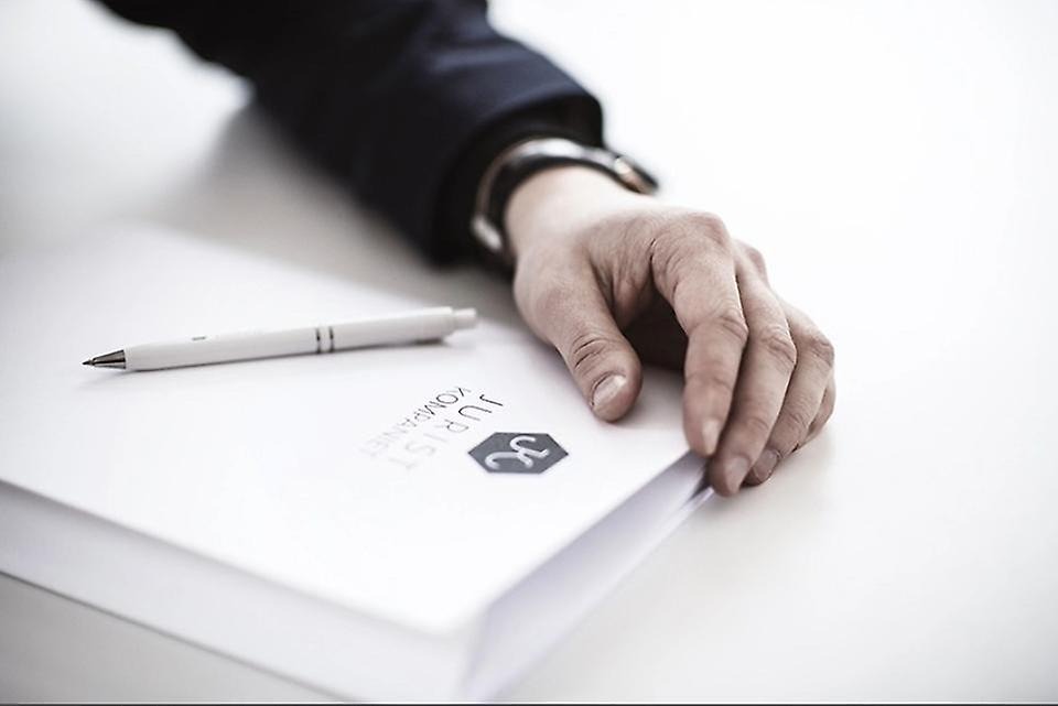 Bild på kostymklädd arm och ett dokument