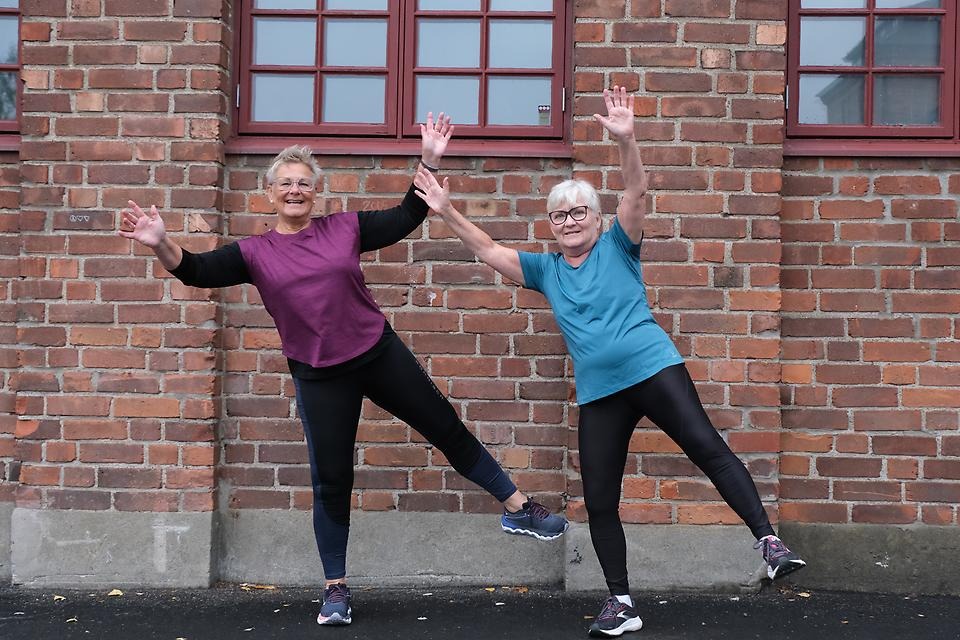 Två glada kvinnor i träningskläder som utför en balansövning