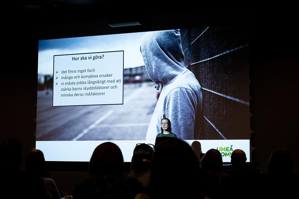 Kvinna står framför presentationsbild med rubriken "Hur ska vi göra?". 
