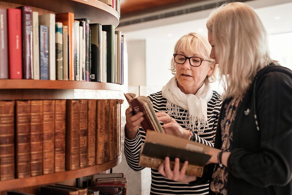 Kvinnor på bibliotek som tittar i en bok