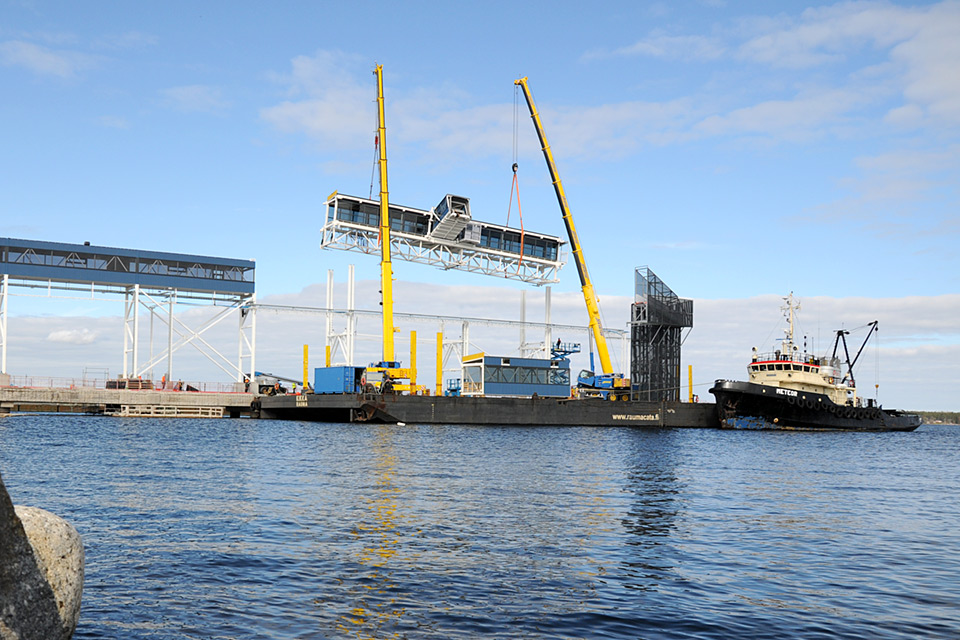 Två lyftkranar lyfter en sektion av en passagerargång på plats i Umeå hamn.