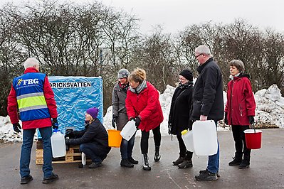 Grupp med människor som får rent dricksvatten i dunkar