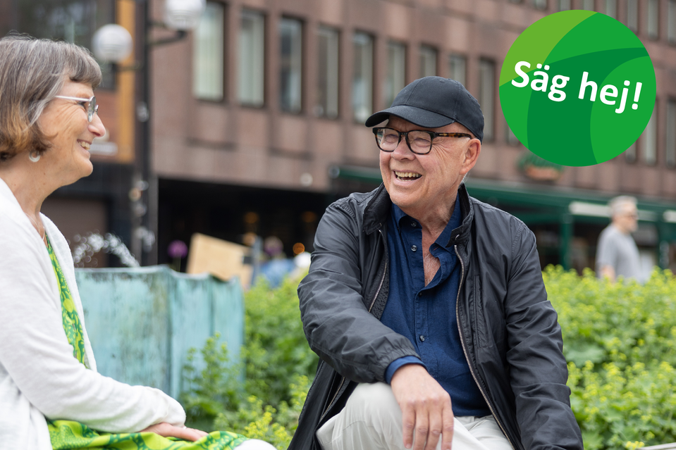 Två glada personer i samtal på en bänk