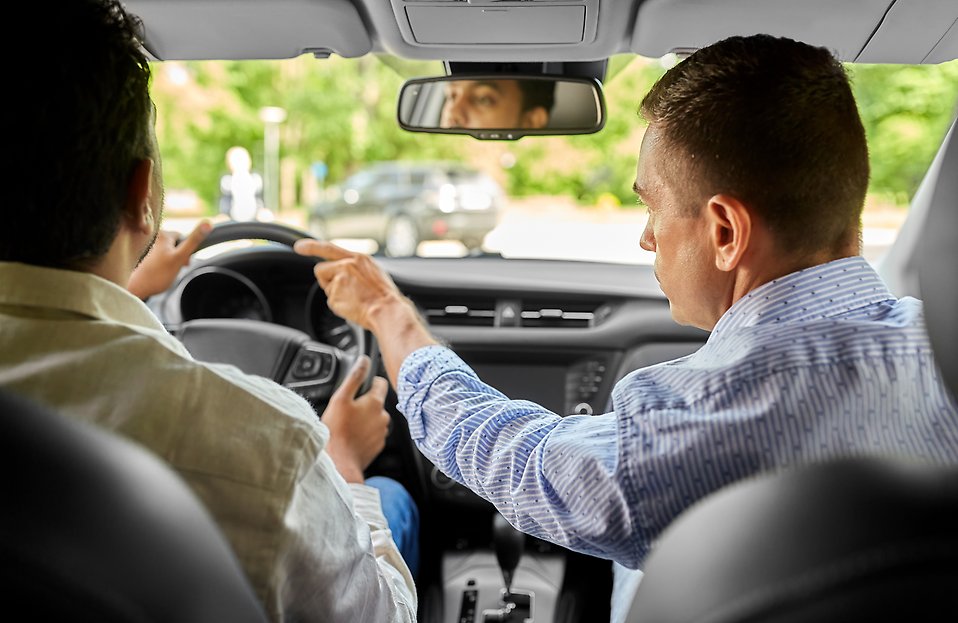 A person tutoring another person in driving a car